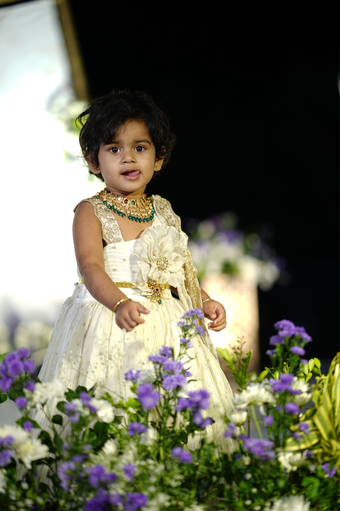 Ivory girls occasion dress with gold details and a sculpted flower